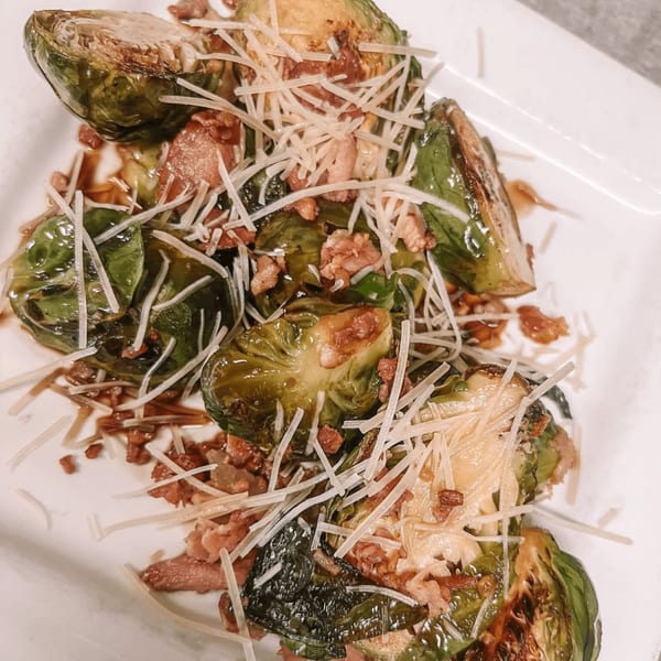 Roasted Brussels sprouts with crispy bacon bits, shredded Parmesan cheese, and a balsamic glaze.
